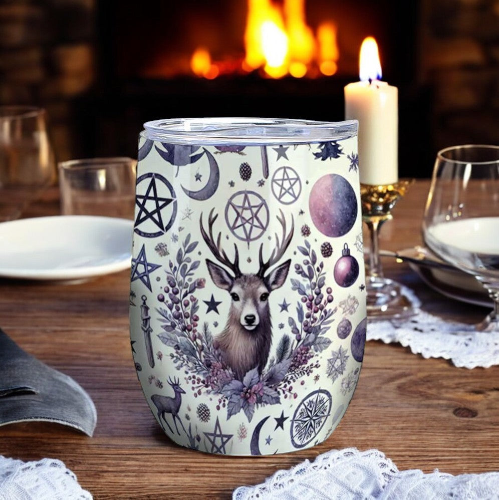 a pagan deer moon pentagram printed 12 oz wine tumbler on a dinner table with a fireplace in the background
